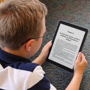 Young boy reading the middle-grade mystery "Room 513" by Jeanna Kunce on a digital tablet