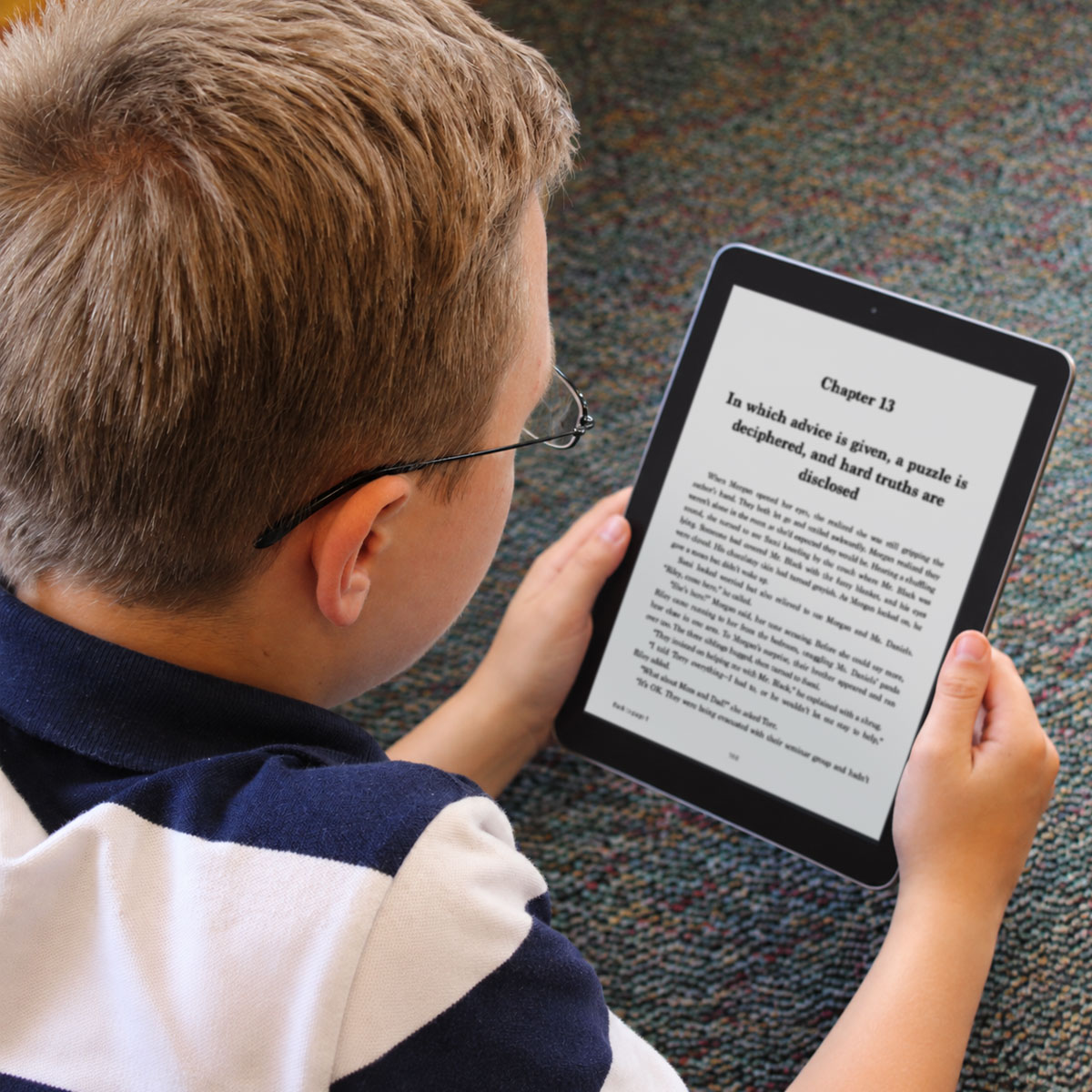 Young boy reading the middle-grade mystery "Room 513" by Jeanna Kunce on a digital tablet