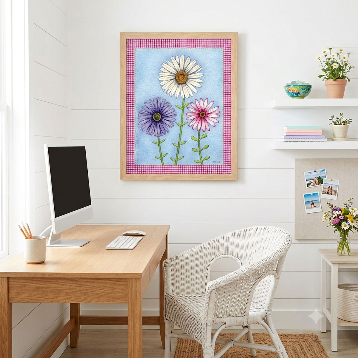 A mock-up photo of a room showing a framed print of a Trio of Daisies Floral Wall Art featuring white, purple, and pink flowers on a blue background with a pink gingham border.