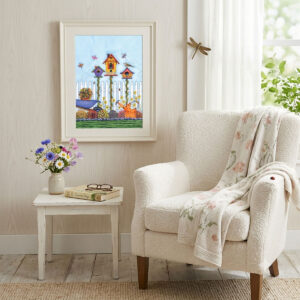 Watercolor art featuring three colorful birdhouses, flowers, dragonflies, and a picket fence - framed on a cottage reading nook wall