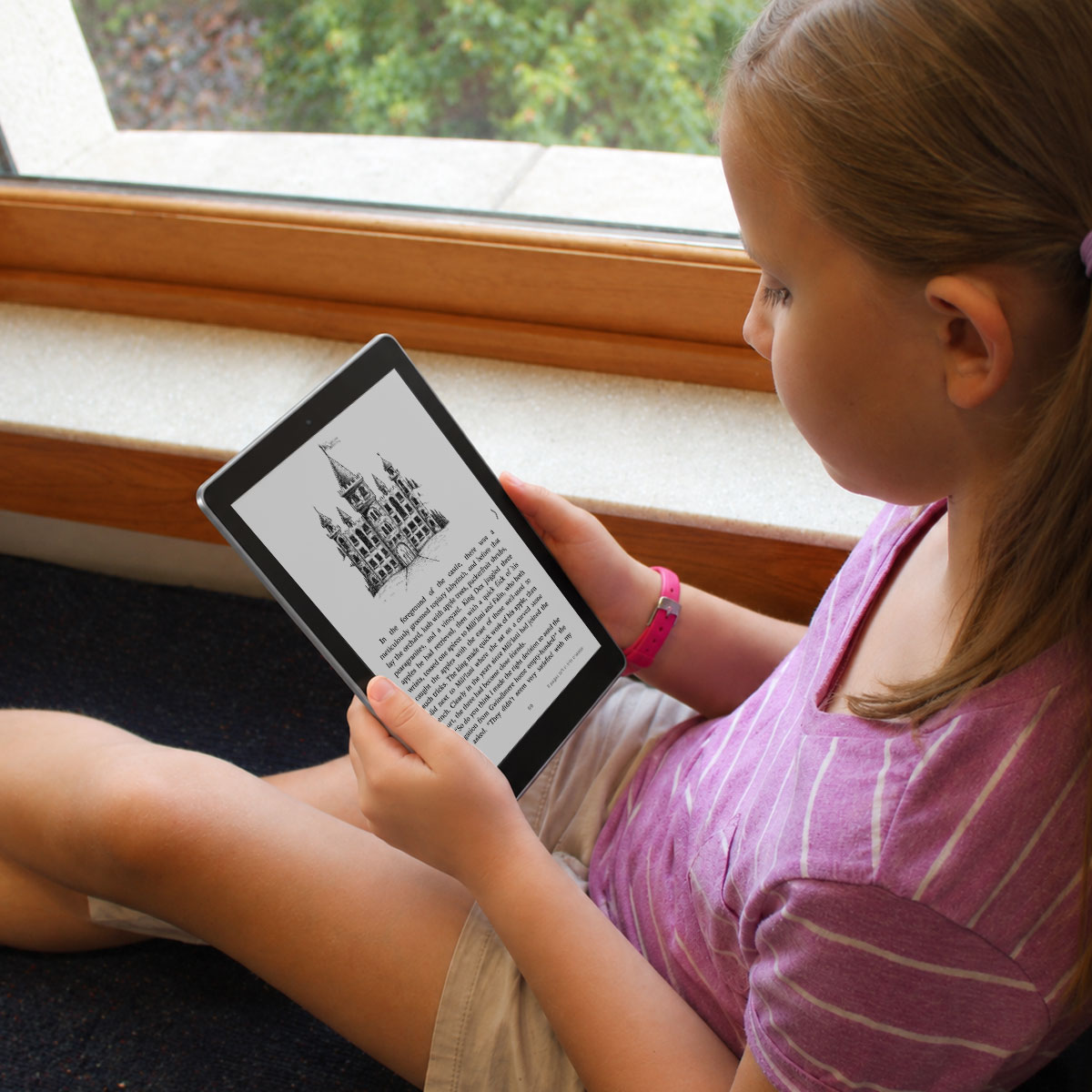 Young girl reading "Darien and the Moonlight Well" by Jeanna Kunce on a digital tablet